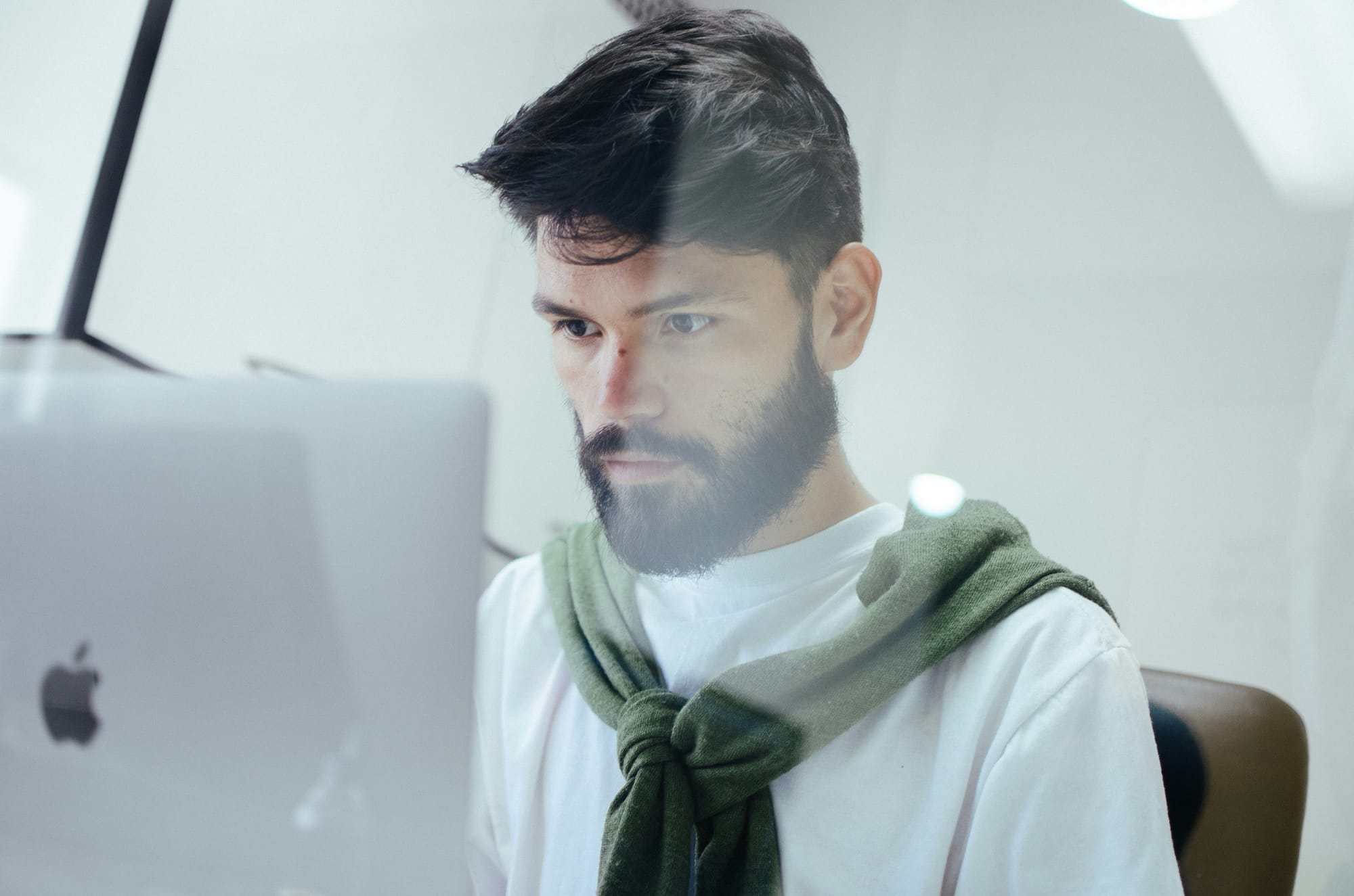 A bearded men looking pensively at a computer screen.